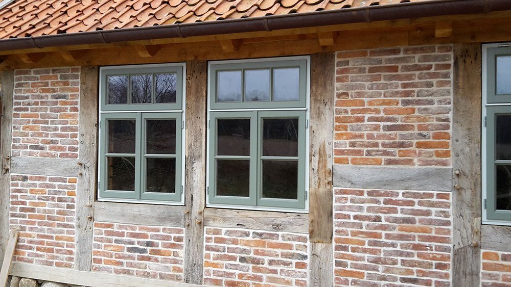 Ein Backsteingebäude mit grünen Fenstern und einem Holzrahmen.