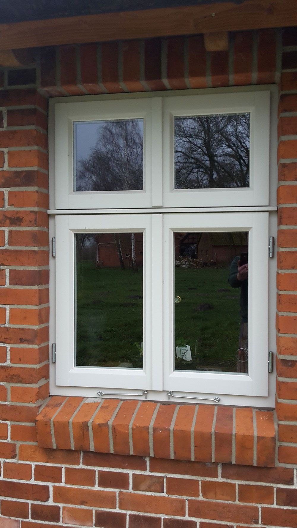 In einer roten Backsteinmauer befindet sich ein weißes Fenster.