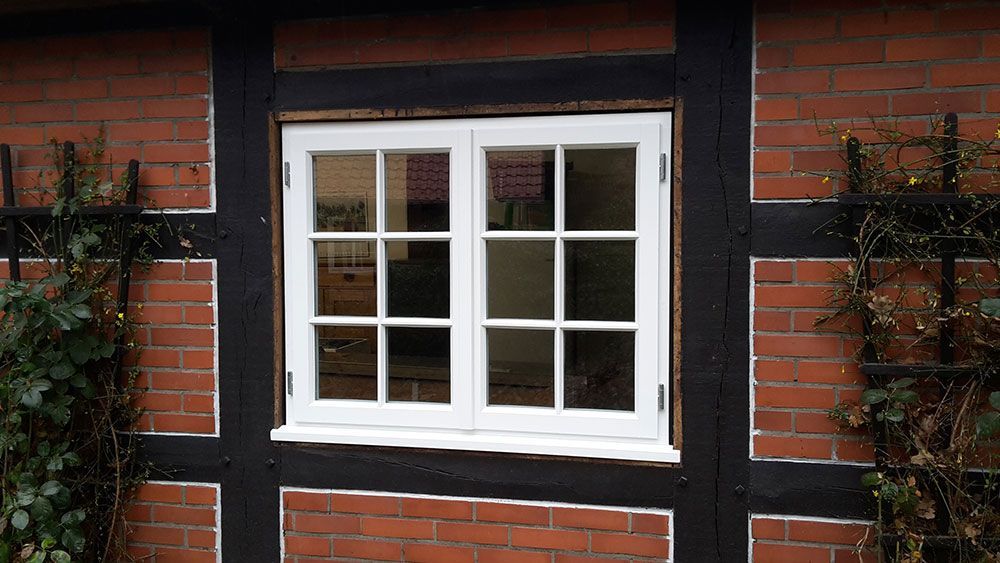 An der Seite eines Backsteingebäudes befindet sich ein weißes Fenster.