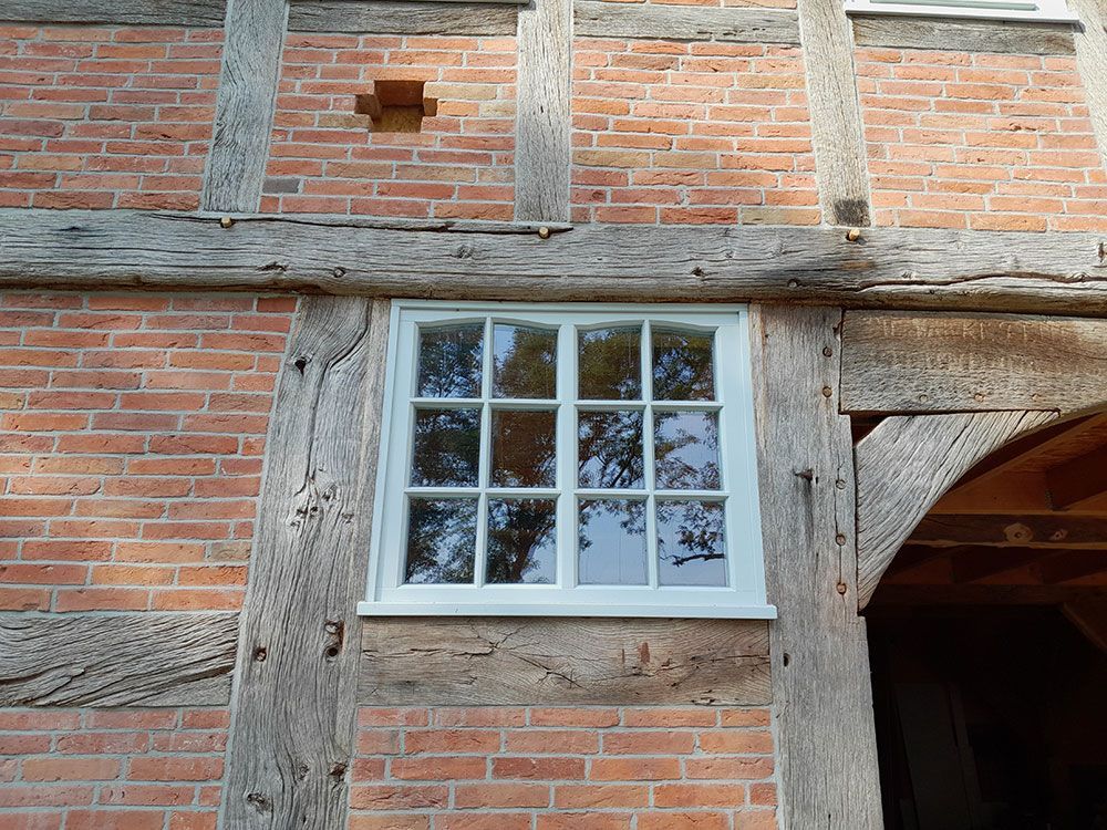 Ein Backsteingebäude mit einem weißen Fenster und Holzbalken