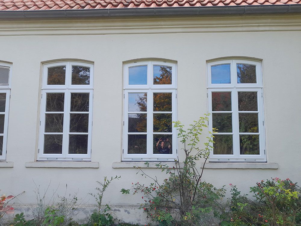 Ein weißes Gebäude mit einem roten Ziegeldach und vielen Fenstern