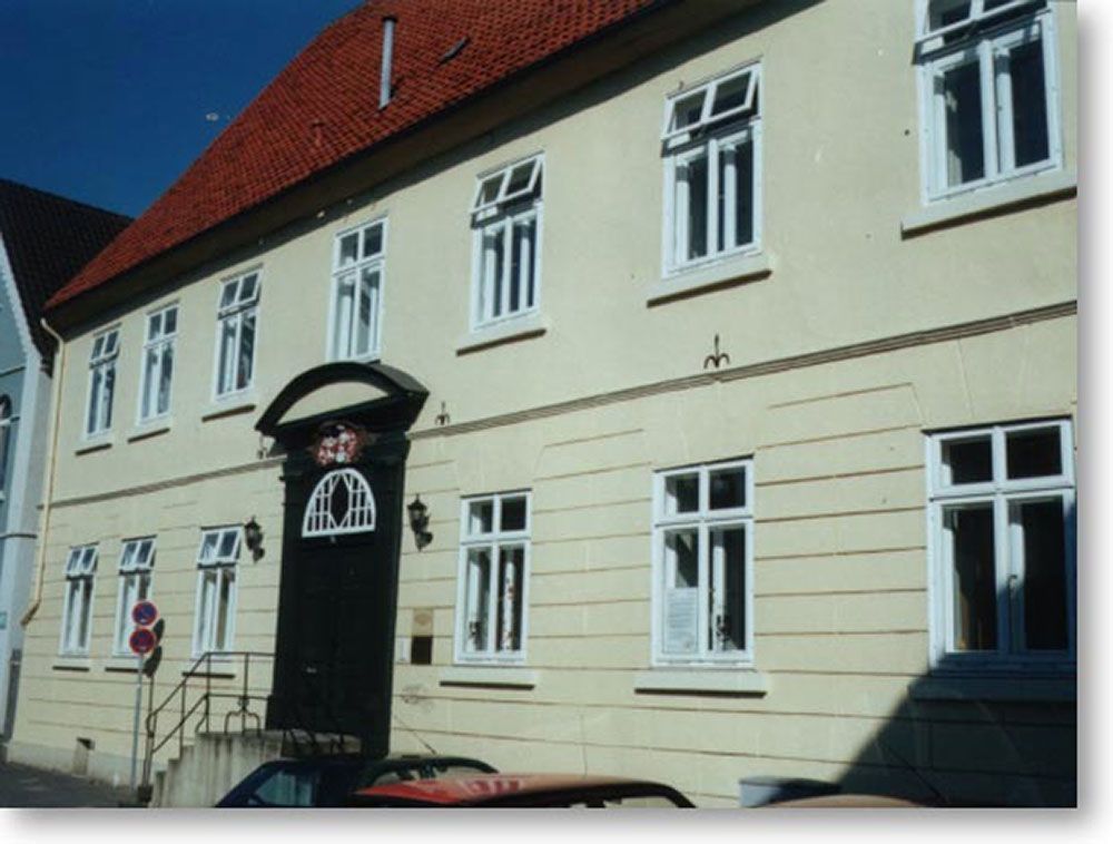 Ein weißes Gebäude mit einem roten Dach und einem davor geparkten schwarzen Auto