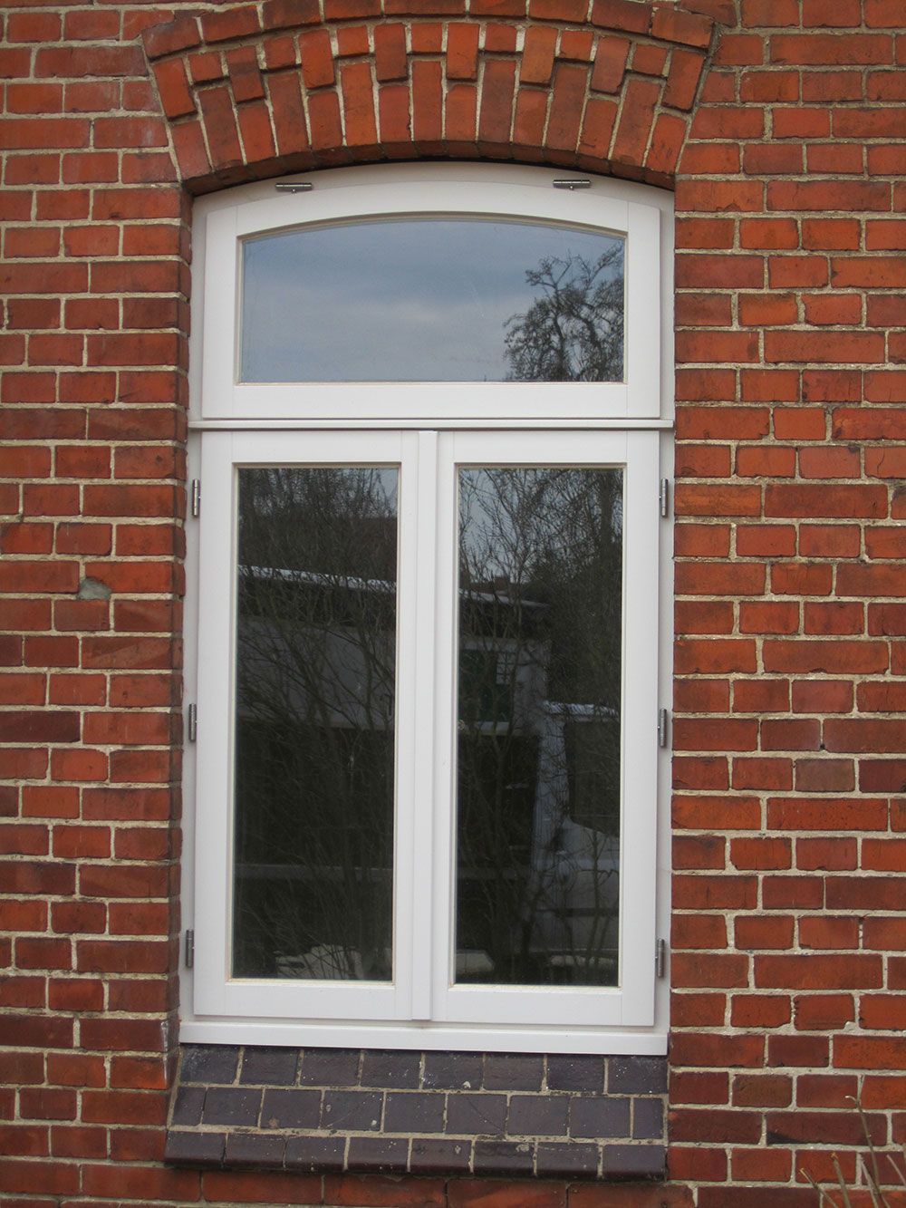 Ein weißes Fenster an einem roten Backsteingebäude