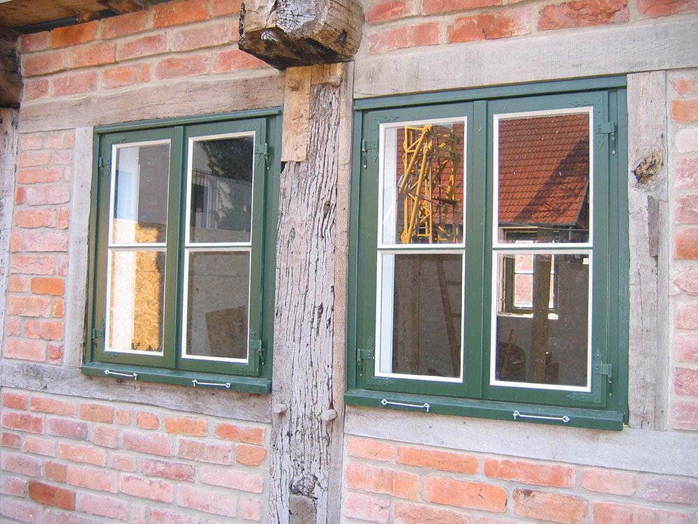 Eine Backsteinmauer mit zwei grünen Fenstern darauf