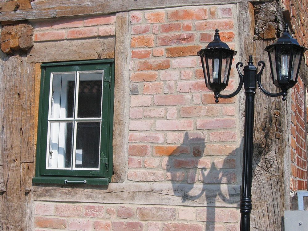 Eine Backsteinmauer mit einem Fenster und zwei Straßenlaternen