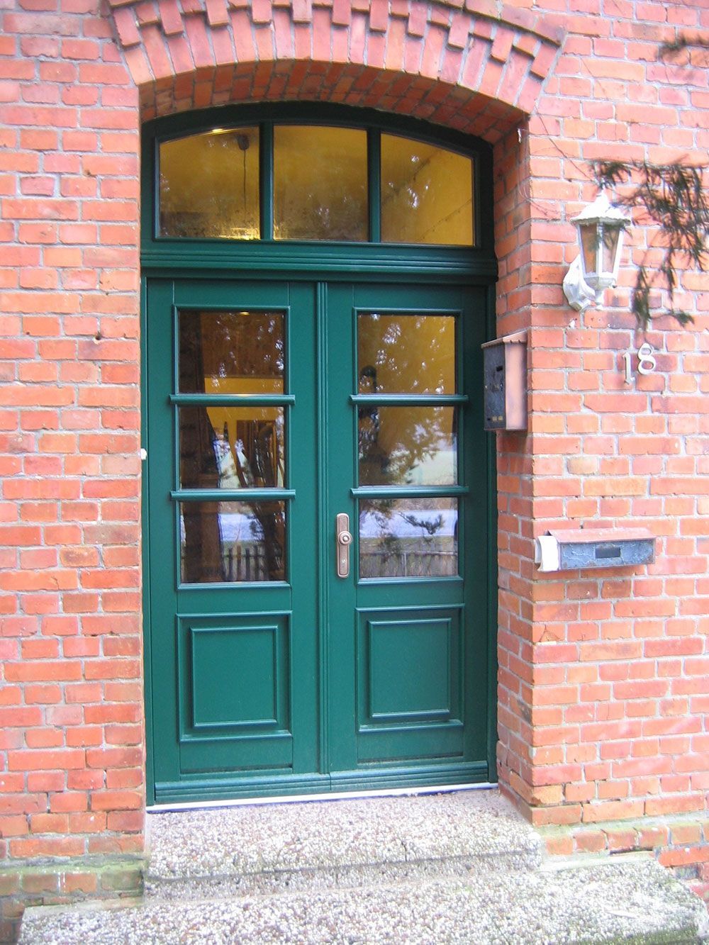 Ein Backsteingebäude mit einer grünen Tür und einem Briefkasten