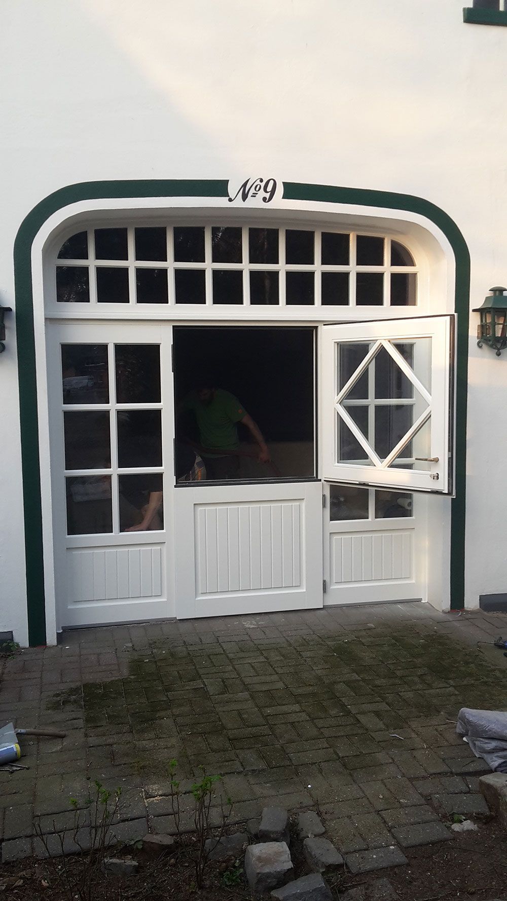 Ein weißes Gebäude mit grüner Verzierung und einer Glasschiebetür