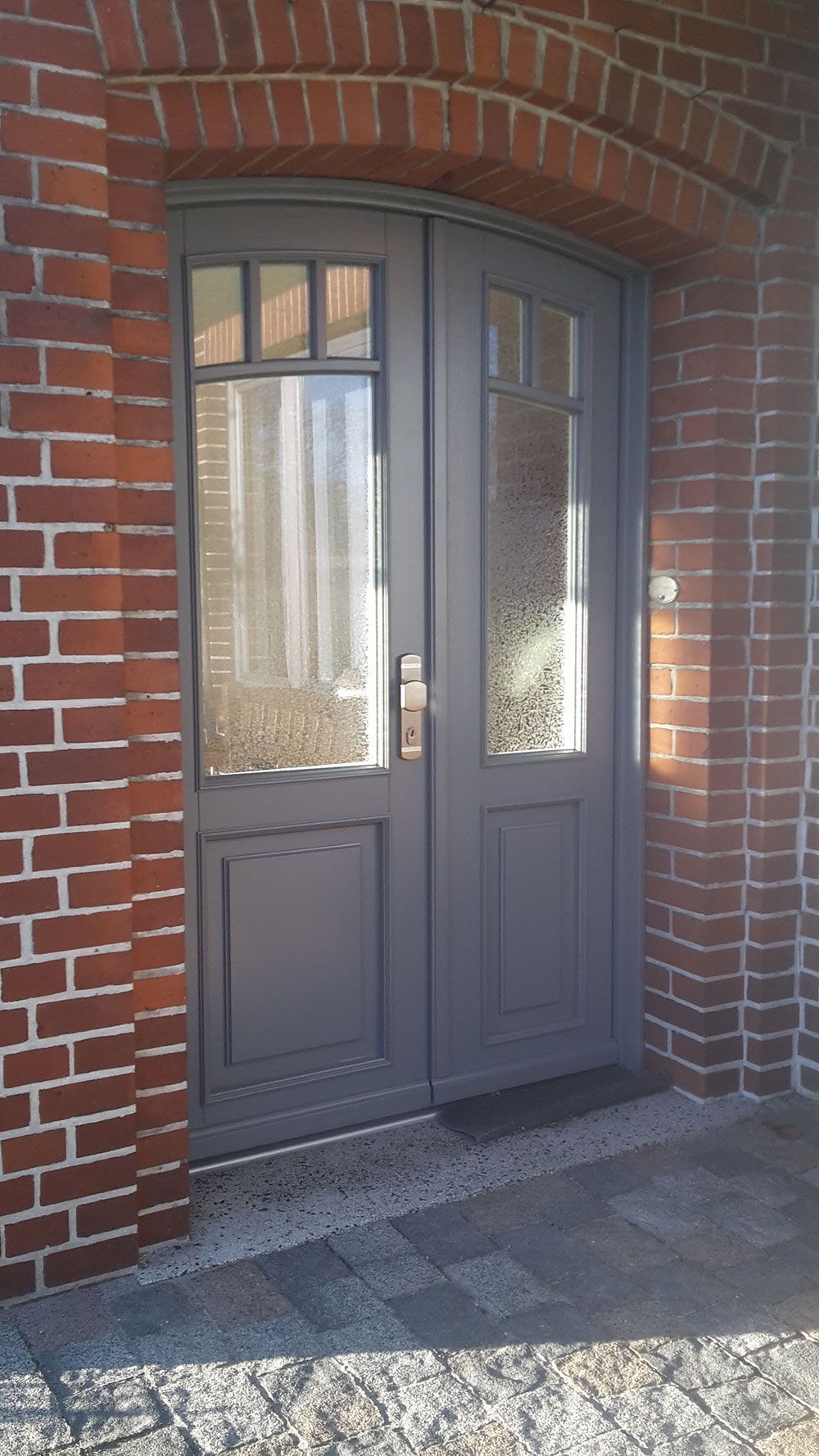 Ein Backsteingebäude mit einer grauen Tür und einer Glastür.