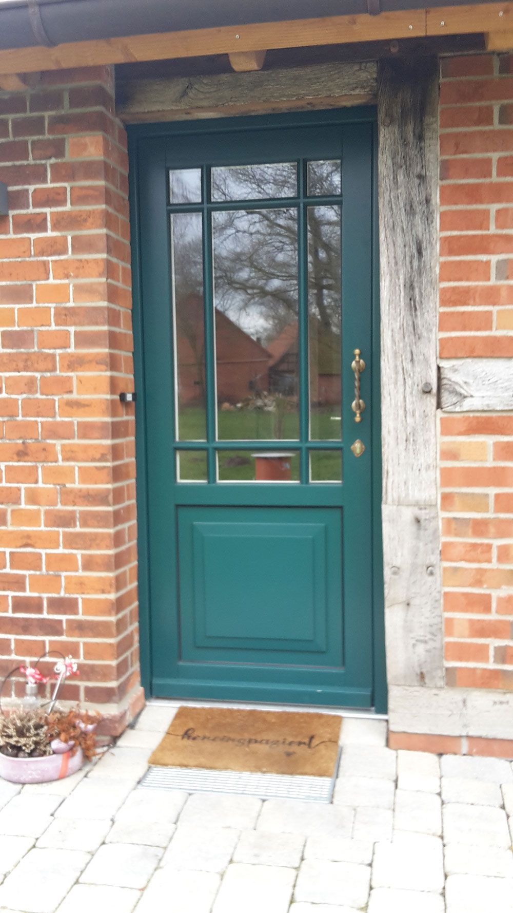 Vor einem Backsteingebäude steht eine grüne Tür.