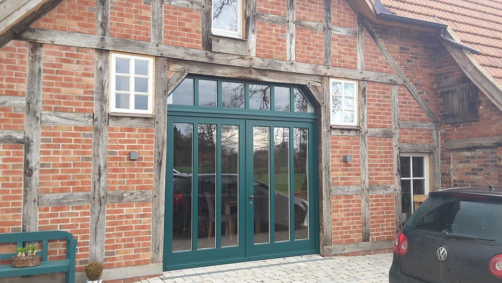 Vor einem Backsteingebäude mit einer grünen Tür parkt ein Auto.