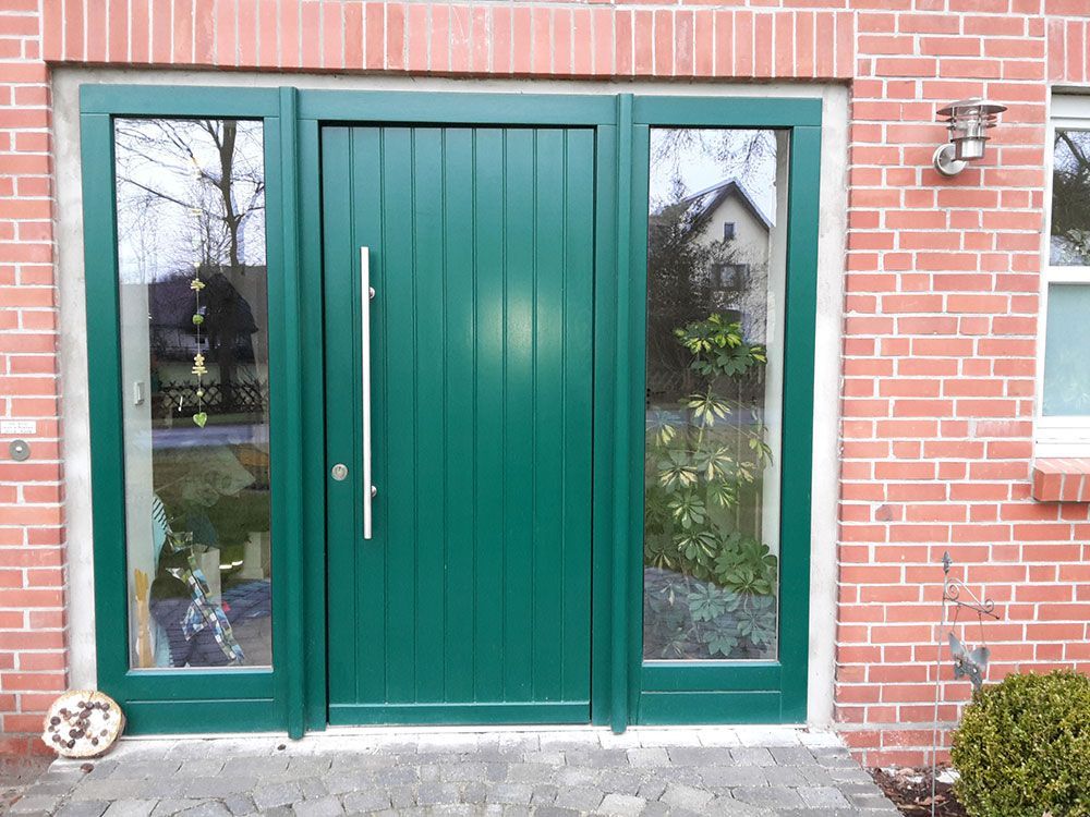 Eine grüne Tür mit einer Ziegelwand dahinter
