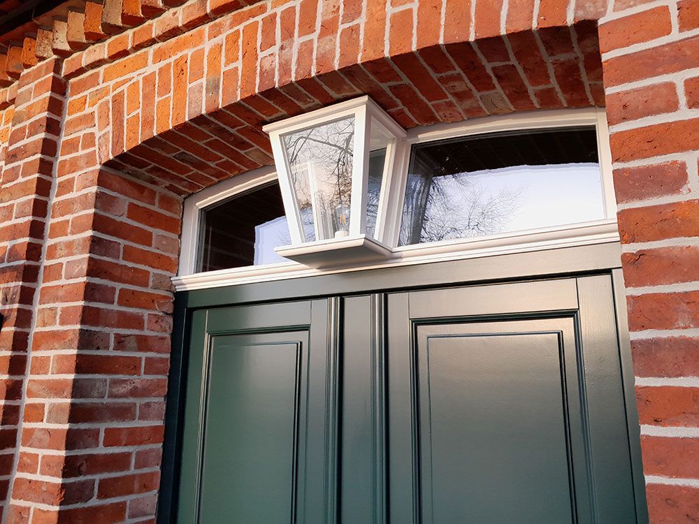 Ein Backsteingebäude mit einer grünen Tür und einer Laterne darauf.
