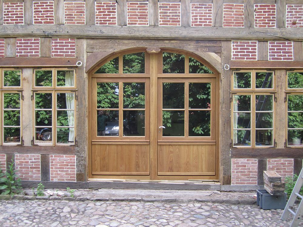 Ein Backsteingebäude mit einer Holztür und Fenstern