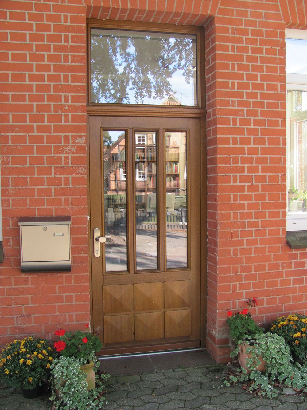 Ein Backsteingebäude mit einer Holztür und Blumen davor