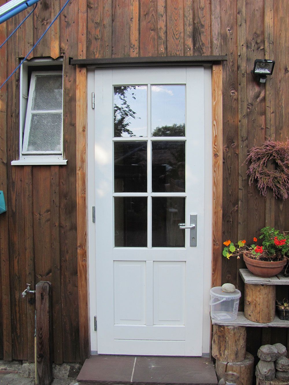 Eine weiße Tür steht vor einer Holzwand