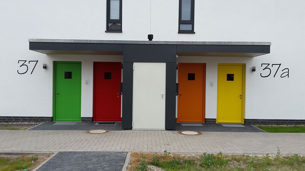 Ein weißes Gebäude mit vier verschiedenfarbigen Türen