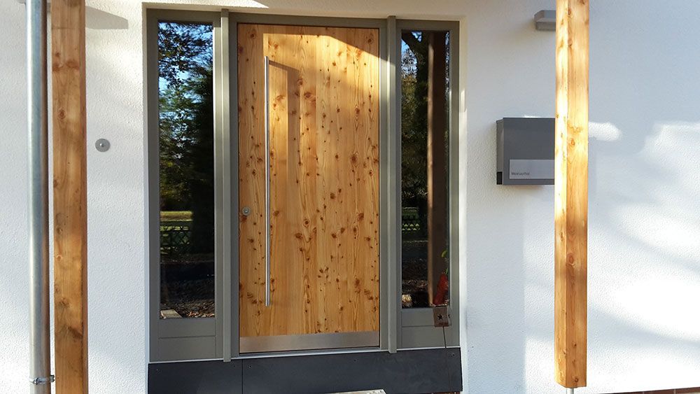 Die Haustür eines Hauses mit einer Holztür und einem Briefkasten.