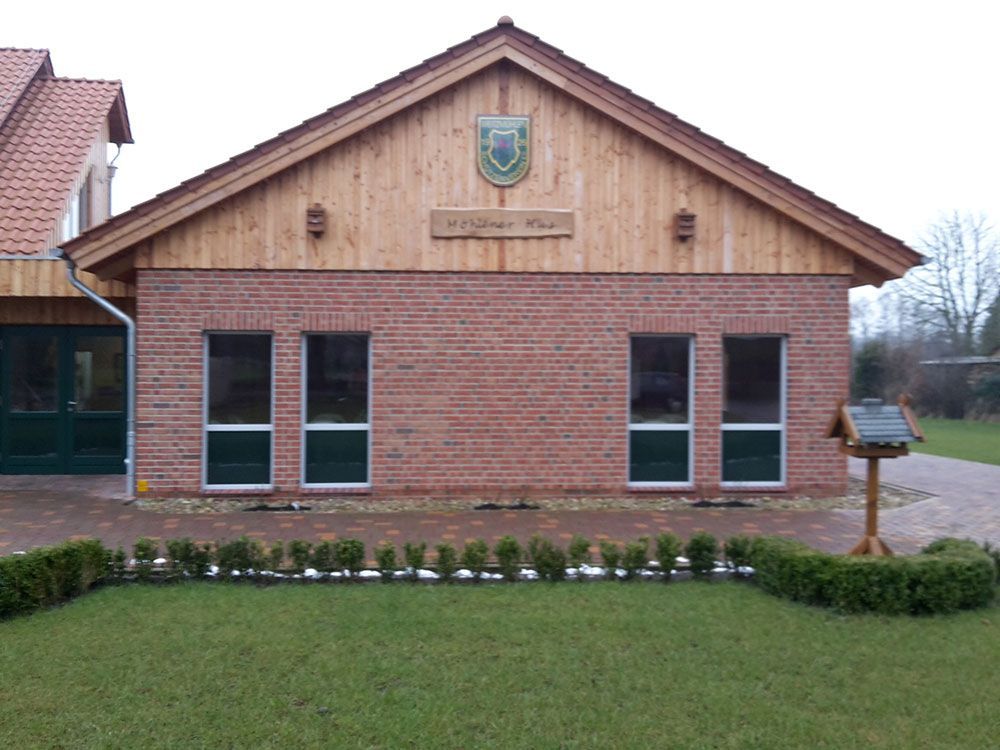 Ein Backsteingebäude mit Holzdach und einem Vogelhäuschen davor