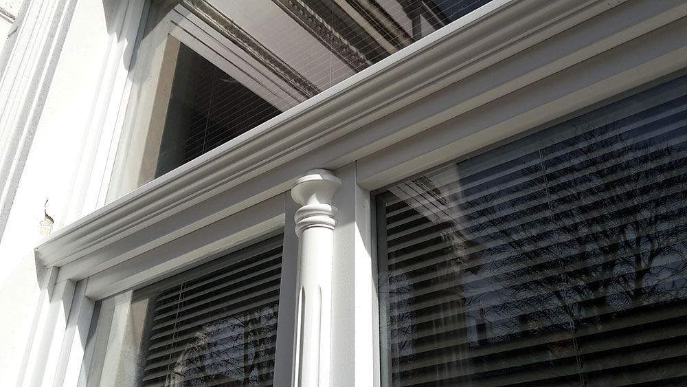 Ein weißes Gebäude mit einem Fenster mit Jalousien.