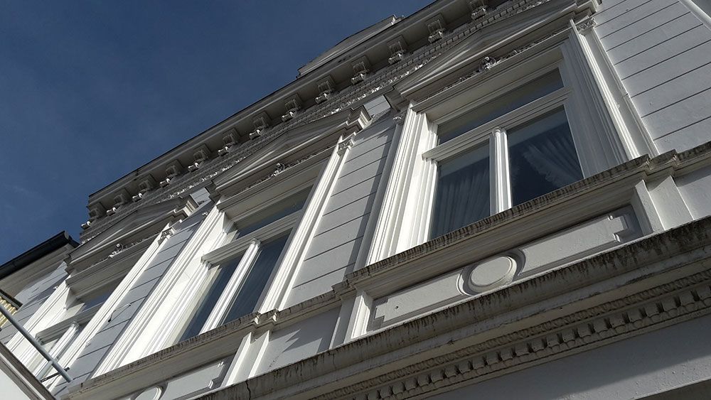 Blick nach oben auf ein weißes Gebäude mit blauem Himmel im Hintergrund