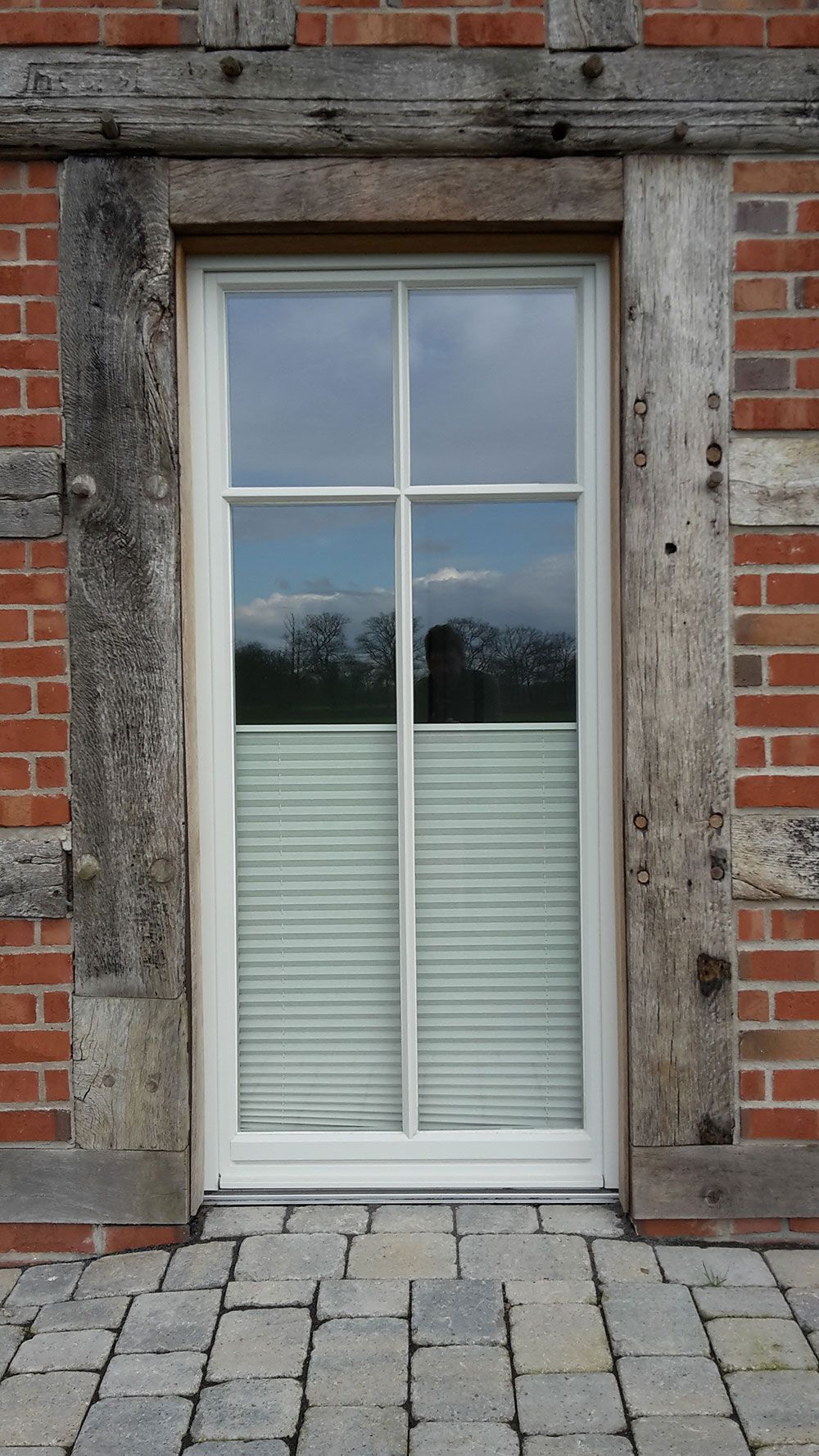 An einem Backsteingebäude befindet sich eine weiße Tür mit Jalousien.