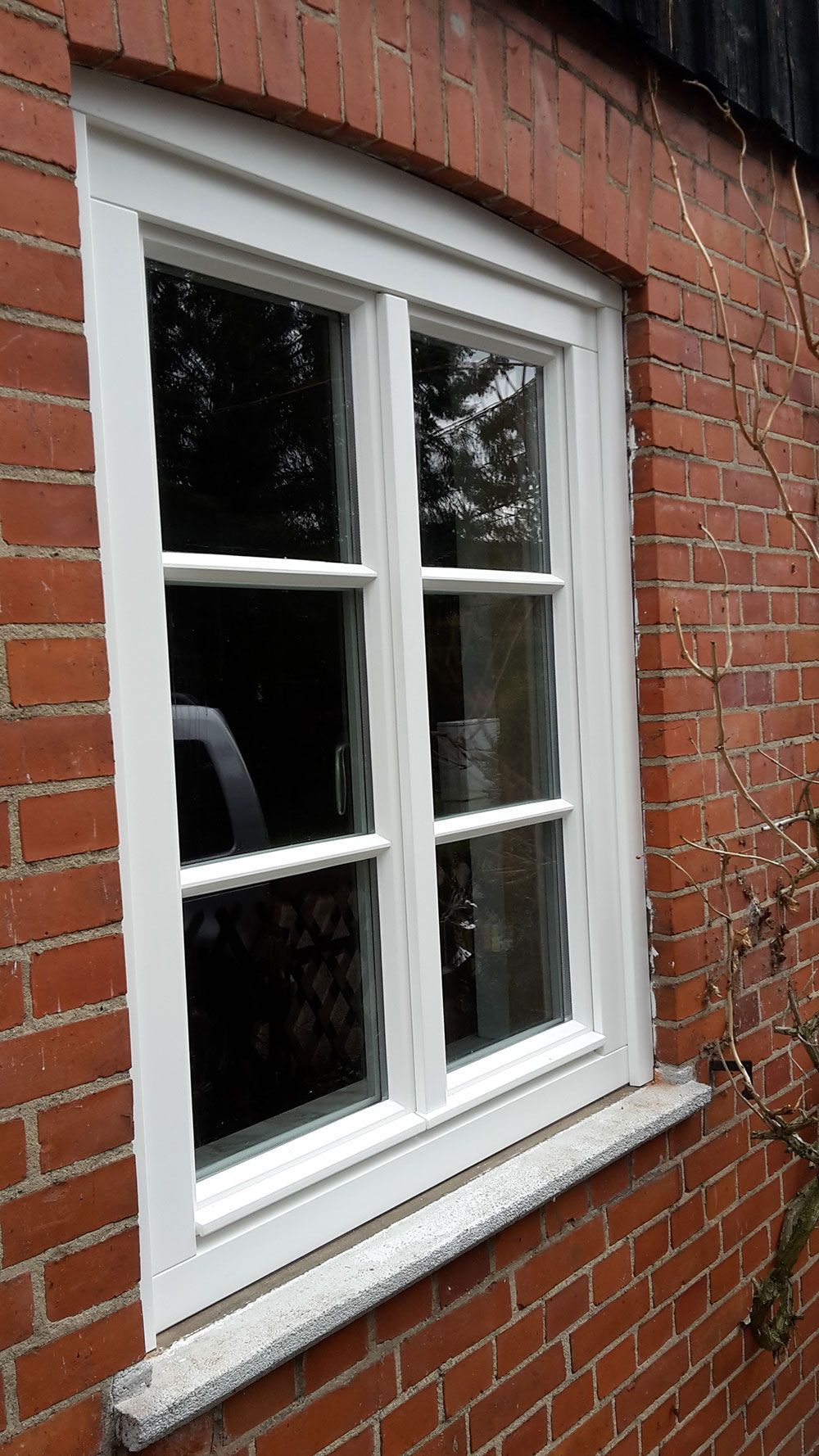 An der Seite eines Backsteingebäudes befindet sich ein weißes Fenster.