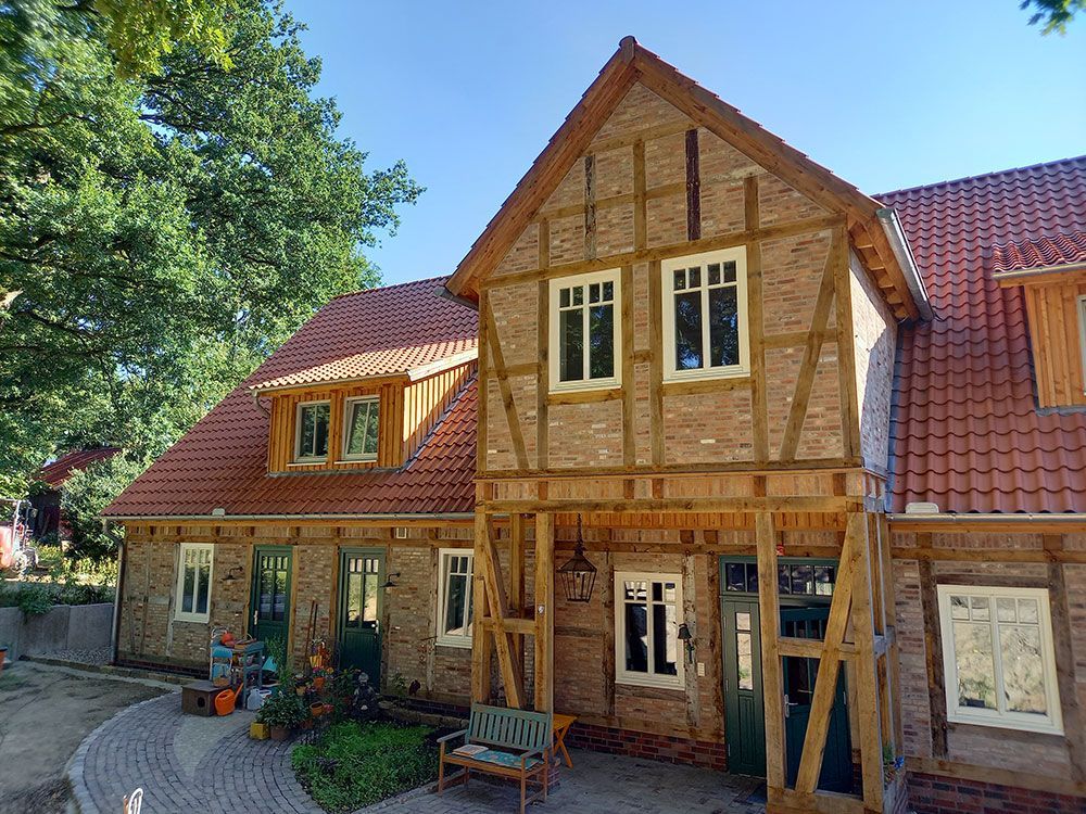 Ein großes Backsteinhaus mit einem roten Ziegeldach und einer Bank davor.