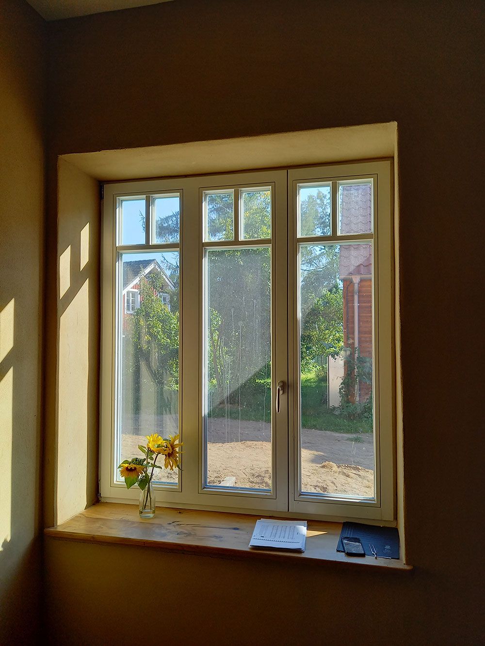 Ein Fenster mit einer Vase mit Blumen auf der Fensterbank.