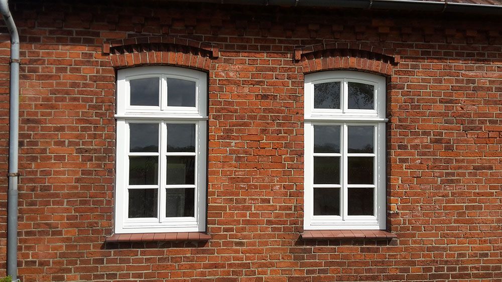 Ein rotes Backsteingebäude mit zwei weißen Fenstern.