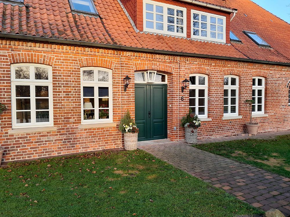 Ein Backsteinhaus mit einer grünen Tür und Fenstern
