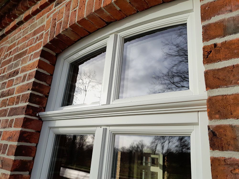 An der Seite eines Backsteingebäudes befindet sich ein weißes Fenster.