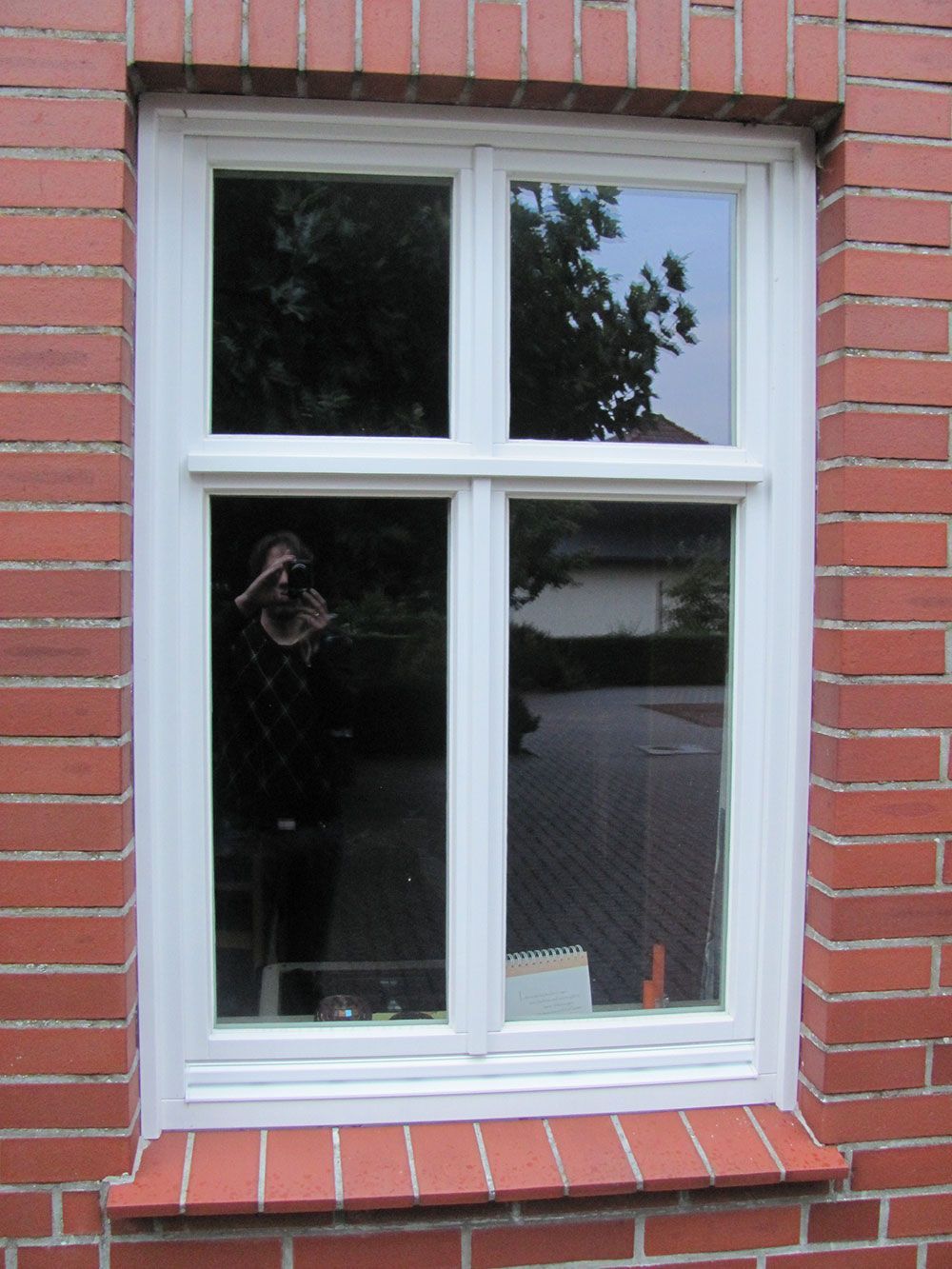 Ein weißes Fenster an einer roten Backsteinmauer