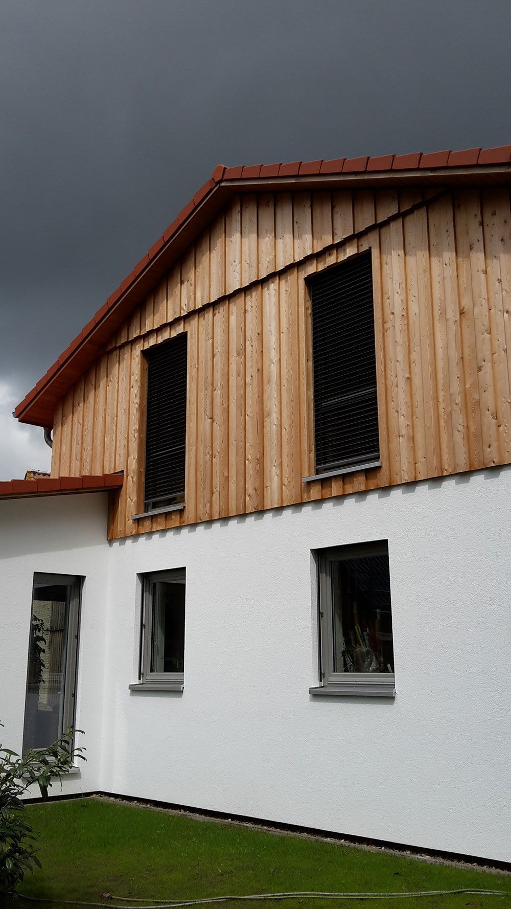 Ein weißes Haus mit einem Holzdach und vielen Fenstern