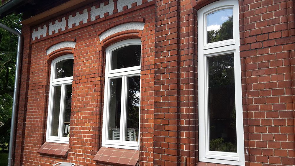 Ein rotes Backsteingebäude mit weißen Fenstern und einem Fallrohr