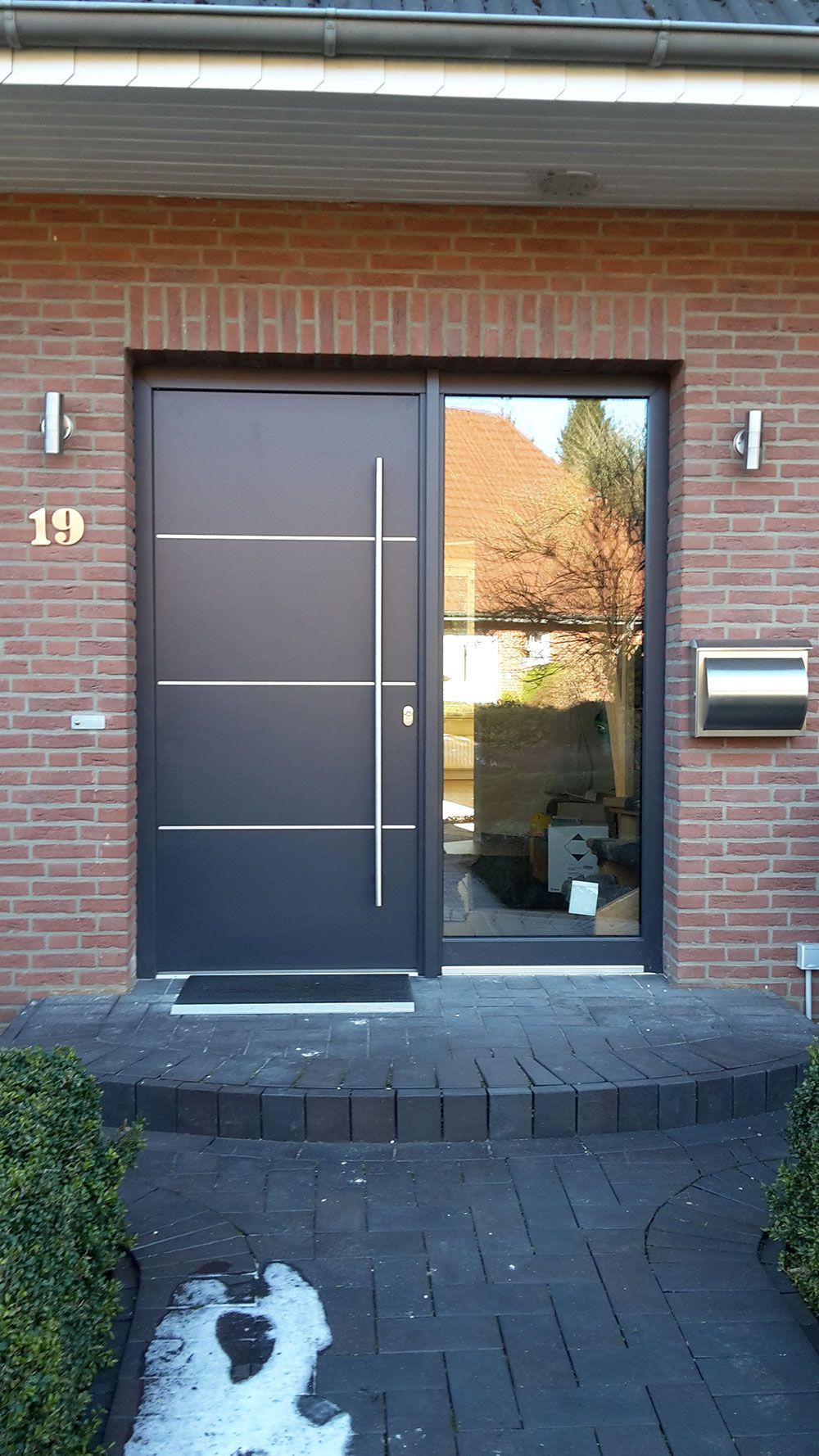 Die Haustür eines Backsteinhauses mit einer schwarzen Tür und einem Briefkasten.