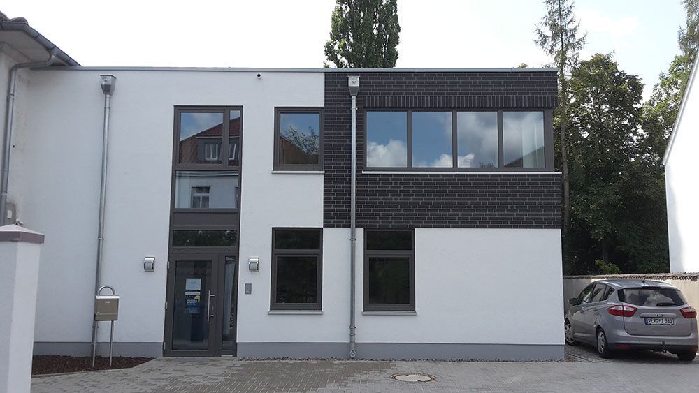 Ein weißes Gebäude mit einem davor geparkten Auto