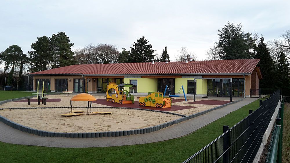 Ein Spielplatz vor einem Gebäude mit rotem Ziegeldach