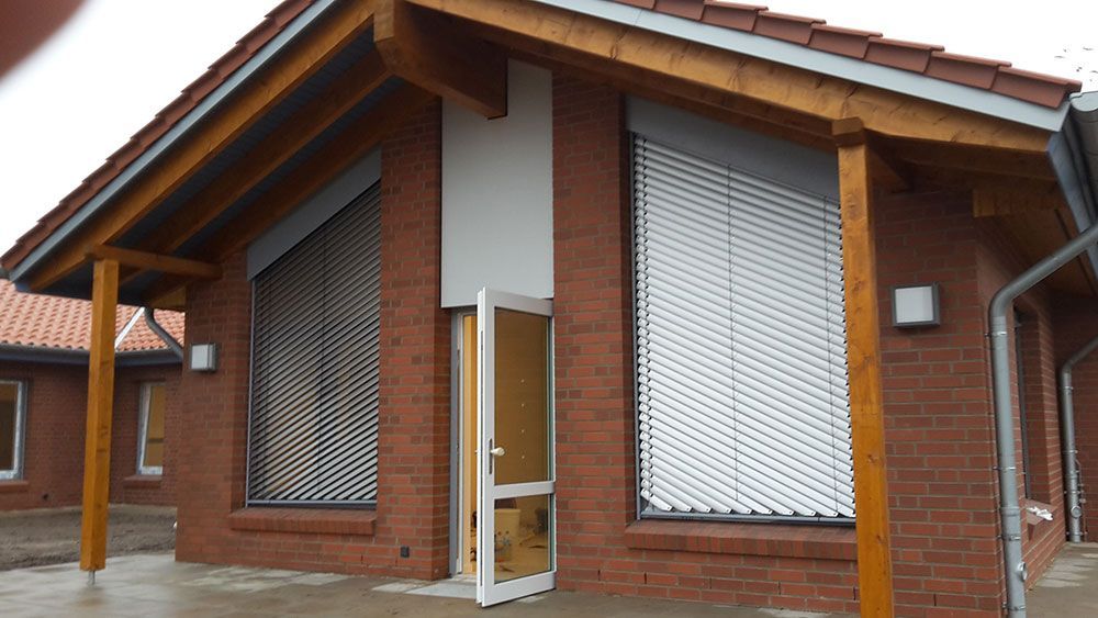 Ein Backsteingebäude mit Holzdach und weißen Jalousien