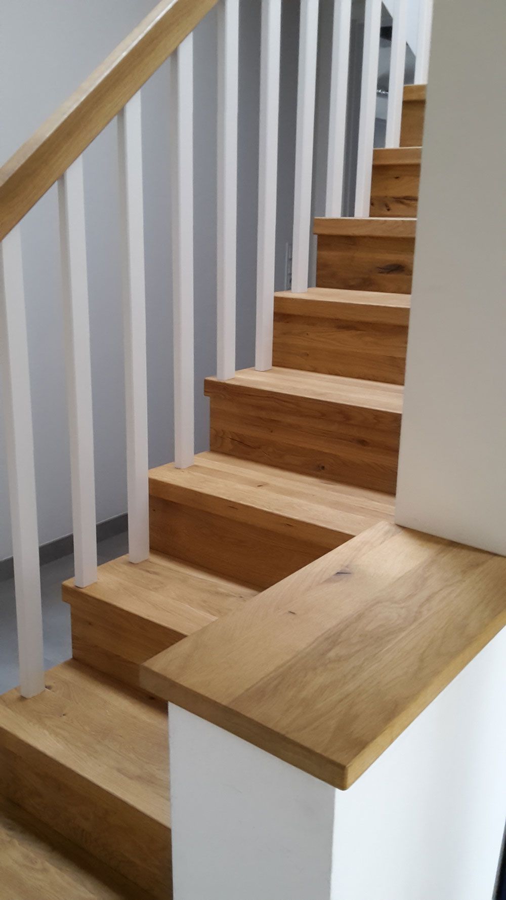 Eine Holztreppe mit einem weißen Geländer in einem Haus.