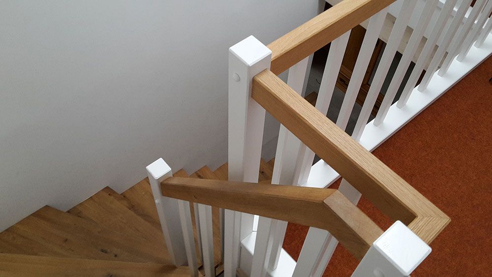 Eine Holztreppe mit weißem Geländer und Holzhandläufen.
