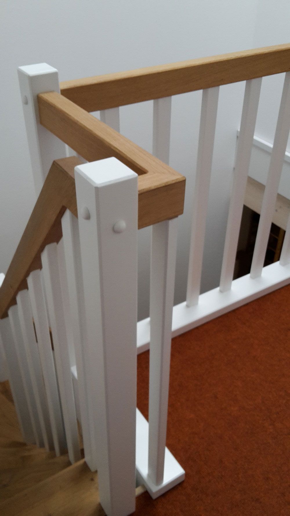 Ein weißes Geländer mit einem Holzhandlauf an einer Treppe.