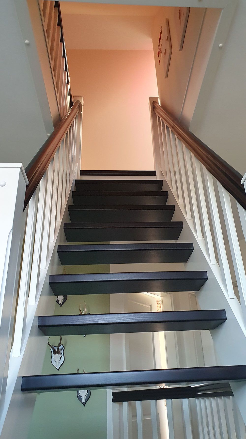 Eine Treppe mit weißem Geländer, die in den zweiten Stock führt.