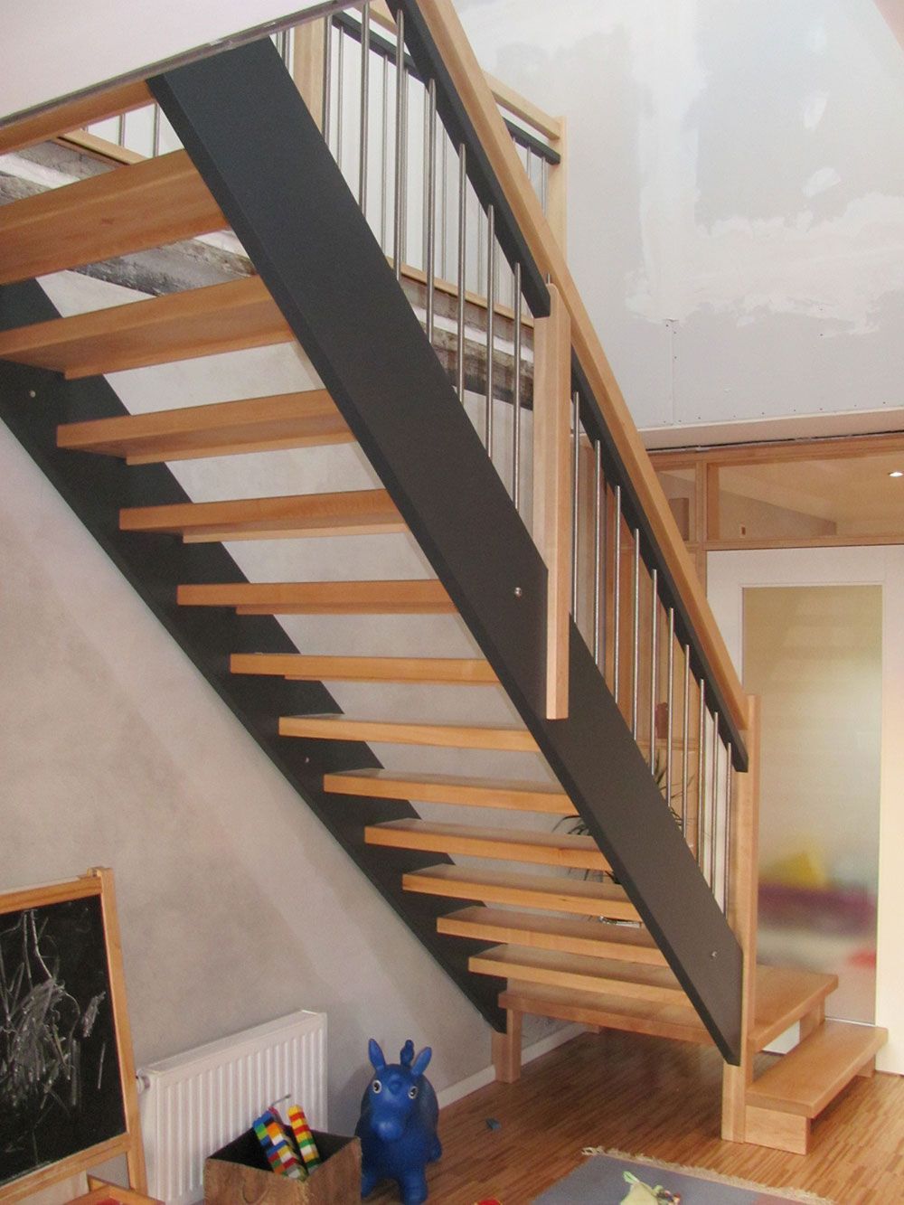 Eine Holztreppe mit schwarzem Geländer in einem Wohnzimmer