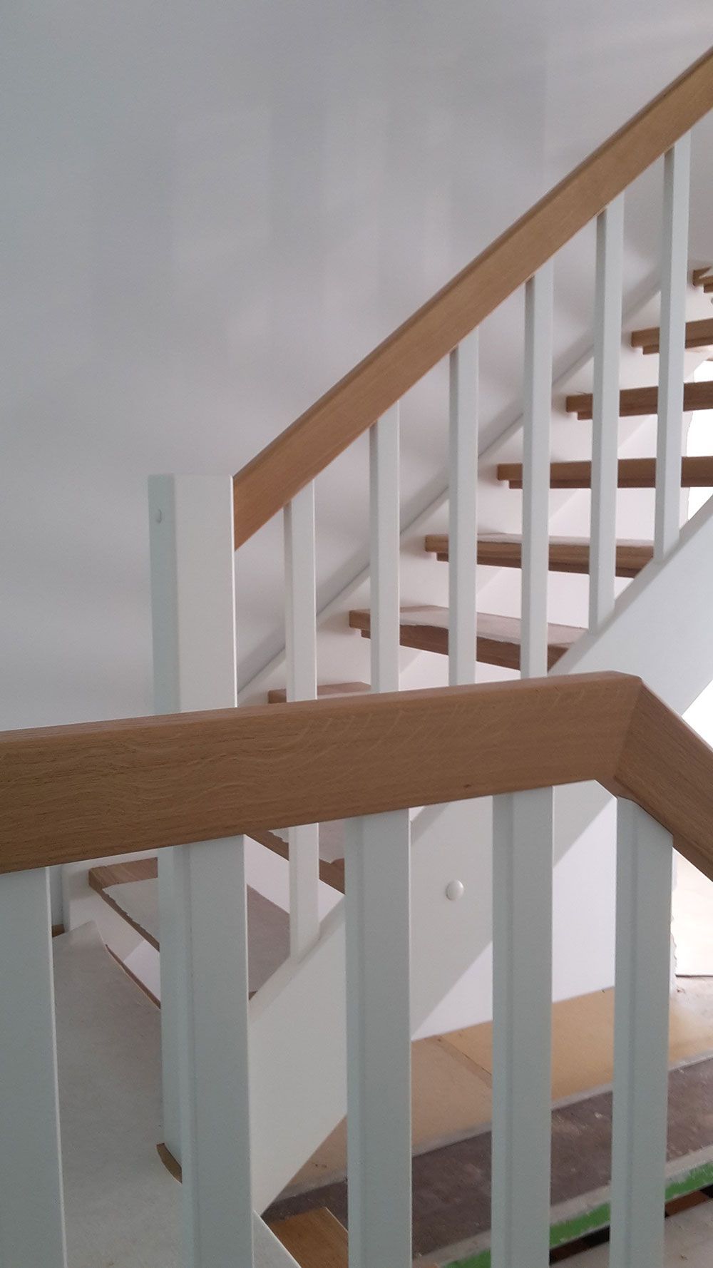 Eine Treppe mit einem weißen Geländer und einem Holzhandlauf