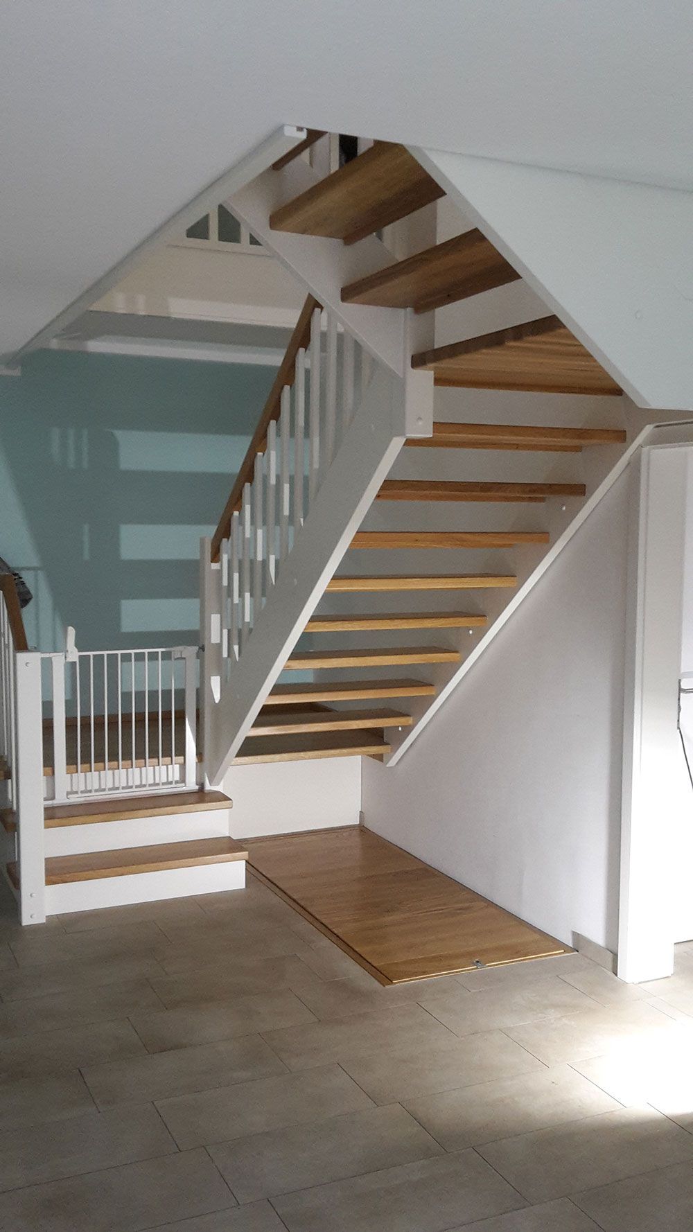 Eine Treppe mit Holzstufen und einem weißen Geländer in einem Raum.