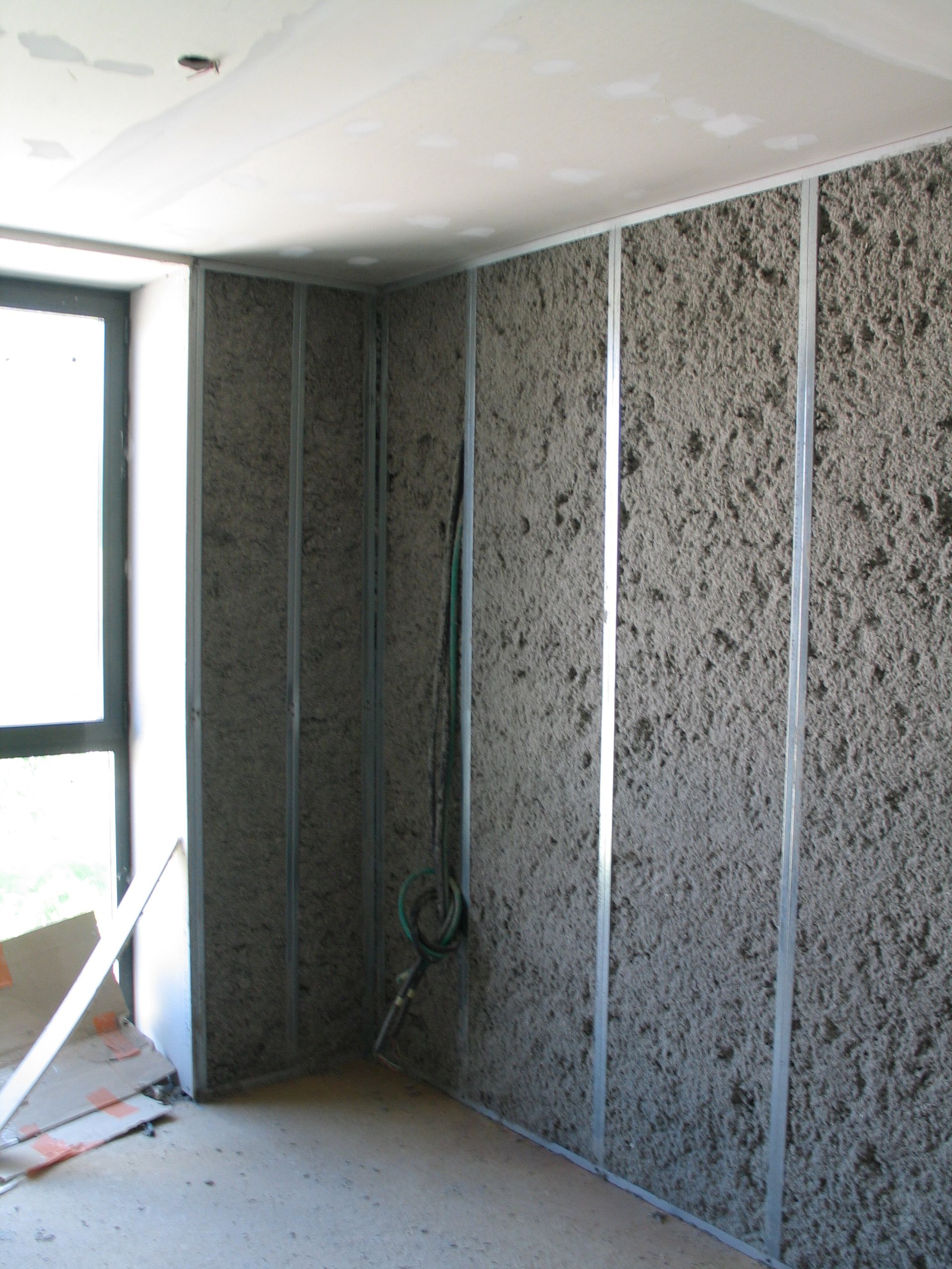 Personne en combinaison de protection installant une isolation dans un mur.