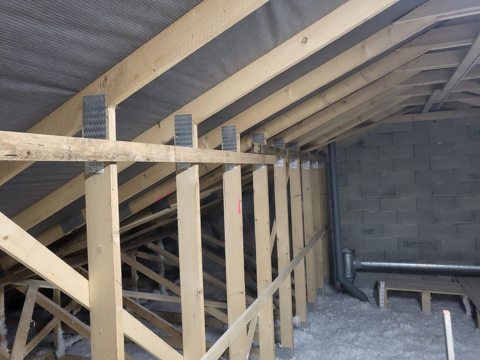 Intérieur des combles avec isolation, poutres apparentes, planches pour plancher.