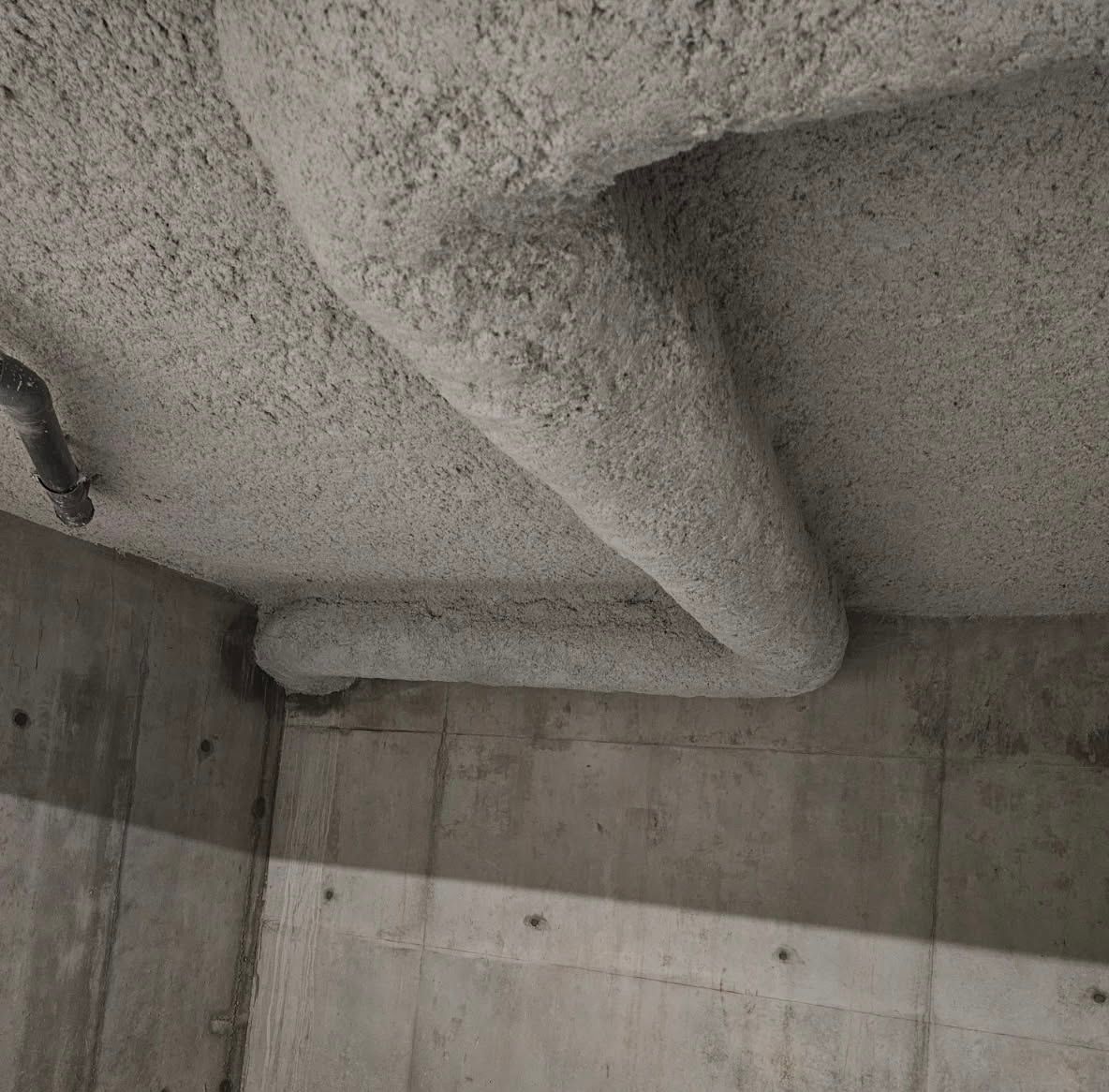 Plafond industriel avec conduits et tuyaux de ventilation métalliques.