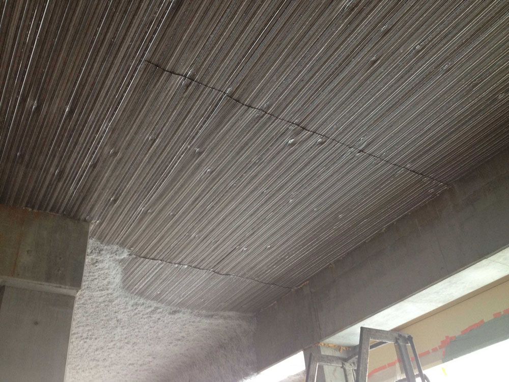 Barres d'armature disposées en grille, prêtes à être coulées dans le plafond d'un bâtiment.