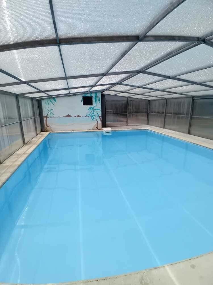 Piscina cubierta climatizada con agua azul y techo arqueado translúcido